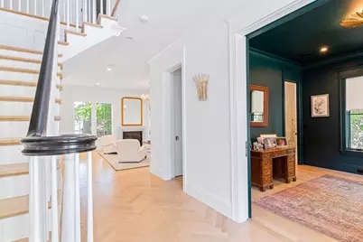 Entry hallway with herringbone floor and staircase, looking toward the library with Salamander green walls